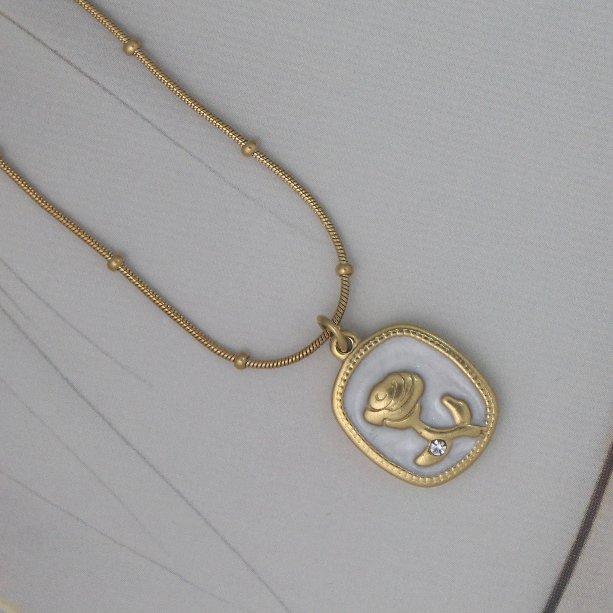 Daily wear Gold anti-tarnish stainless steel chain with a rose pendant with a diamond on a gray background