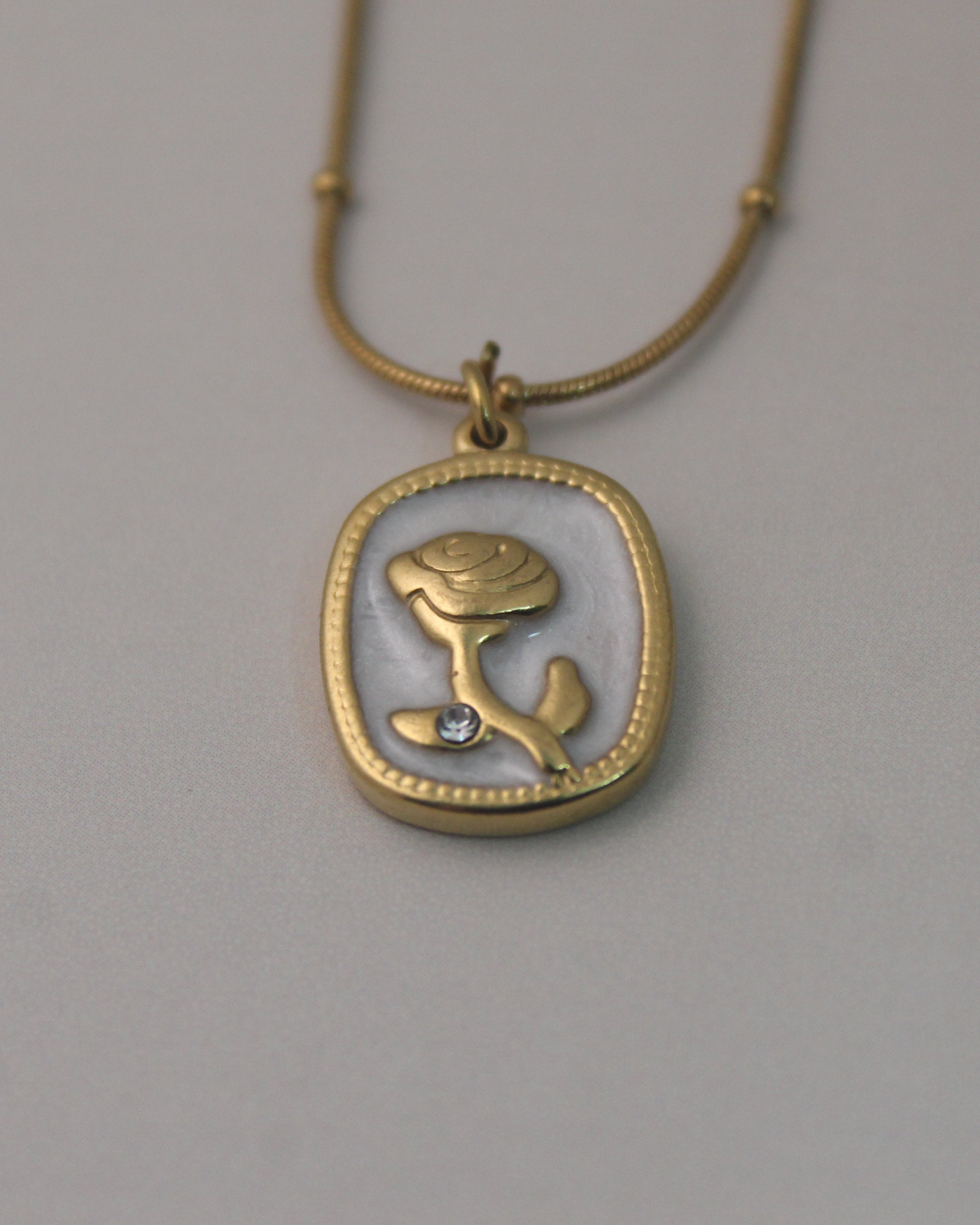 Daily wear Gold anti-tarnish stainless steel chain with a rose pendant with a diamond on a gray background