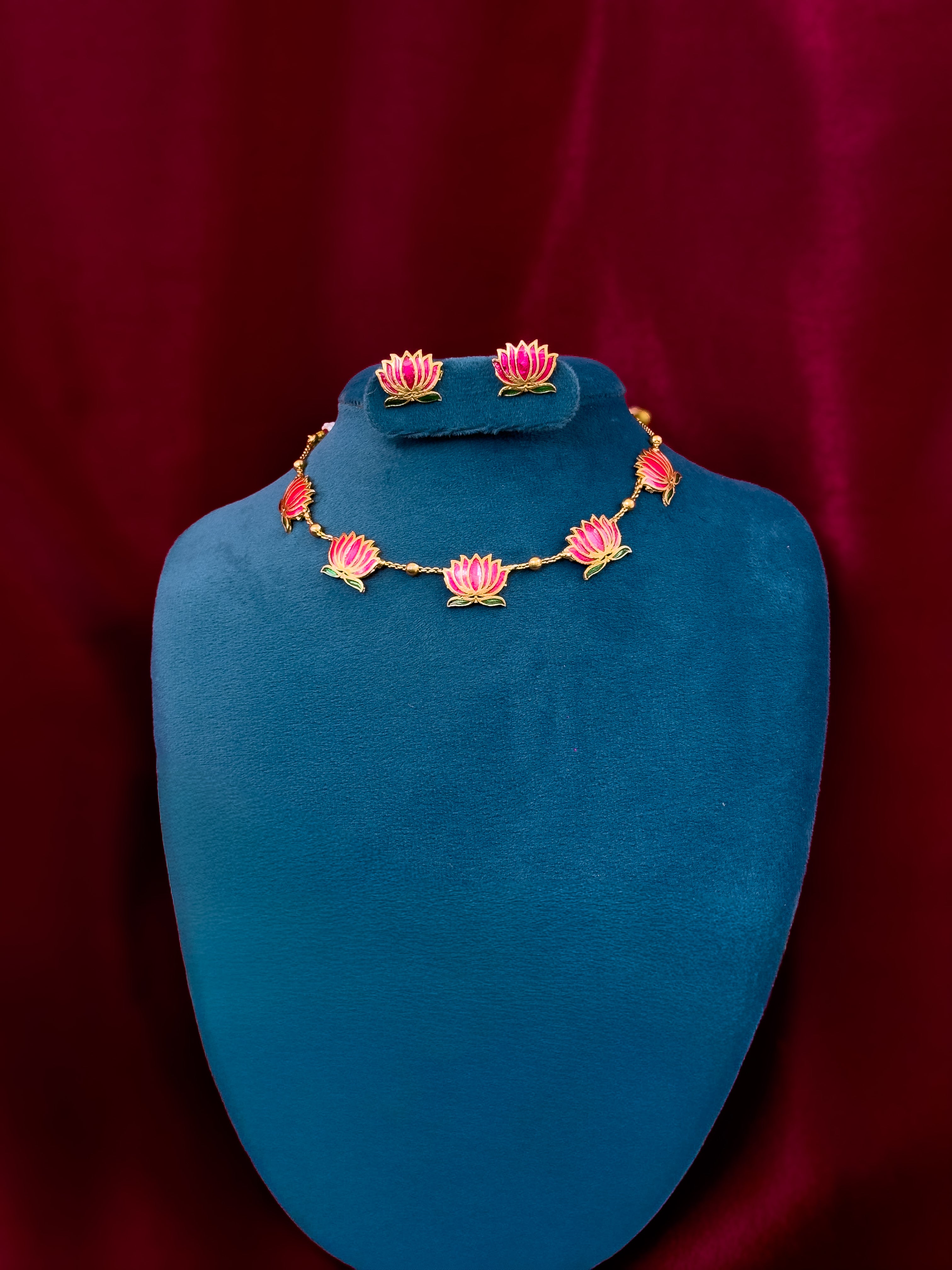 Traditional lotus necklace swith matching earrings  on a blue stand against a red background