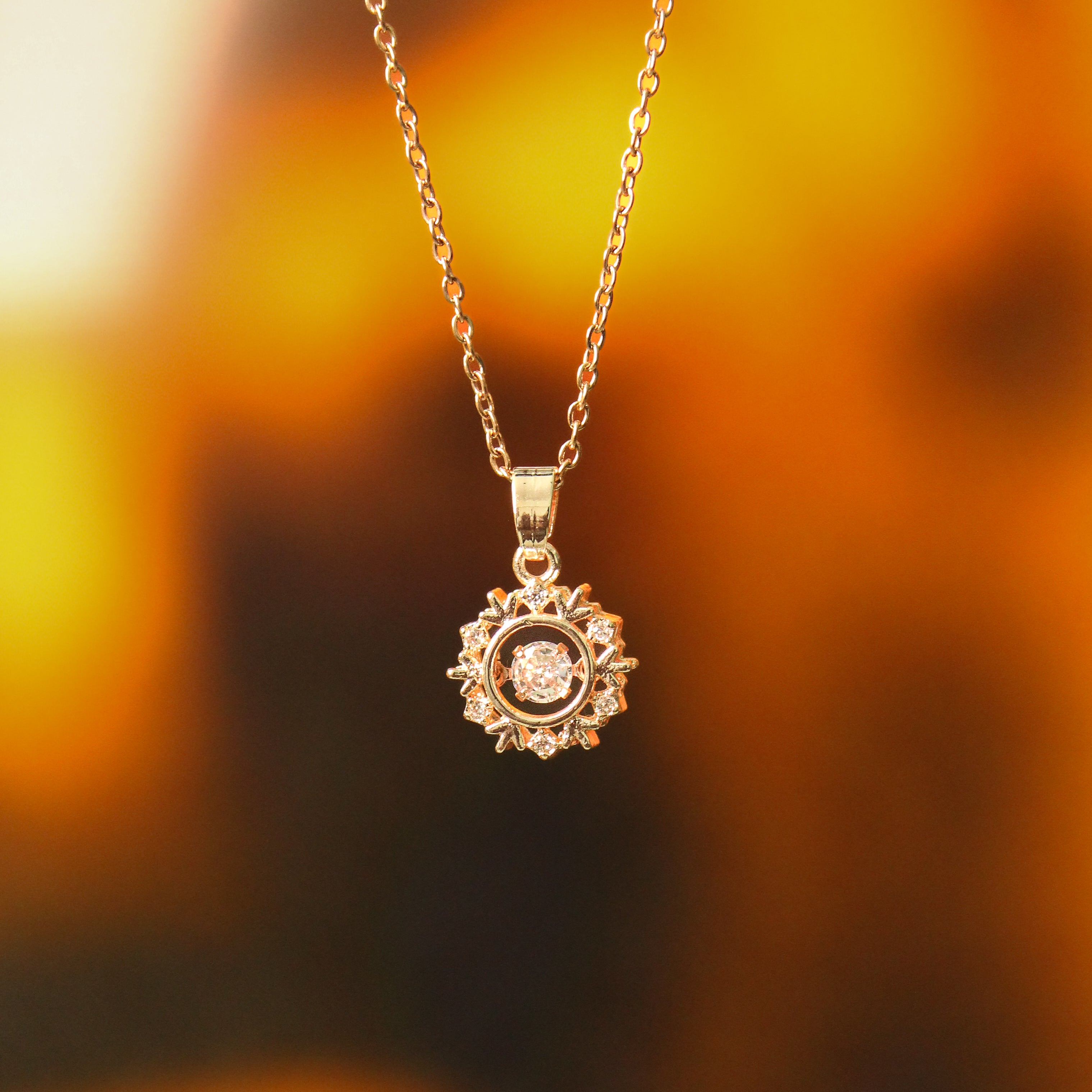 Gold necklace with a sunflower-shaped pendant against a blurred autumn background